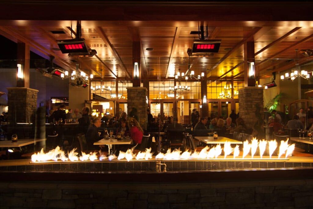 Restaurante bullicioso y poco iluminado, con una encimera de fuego y calefactores de gas