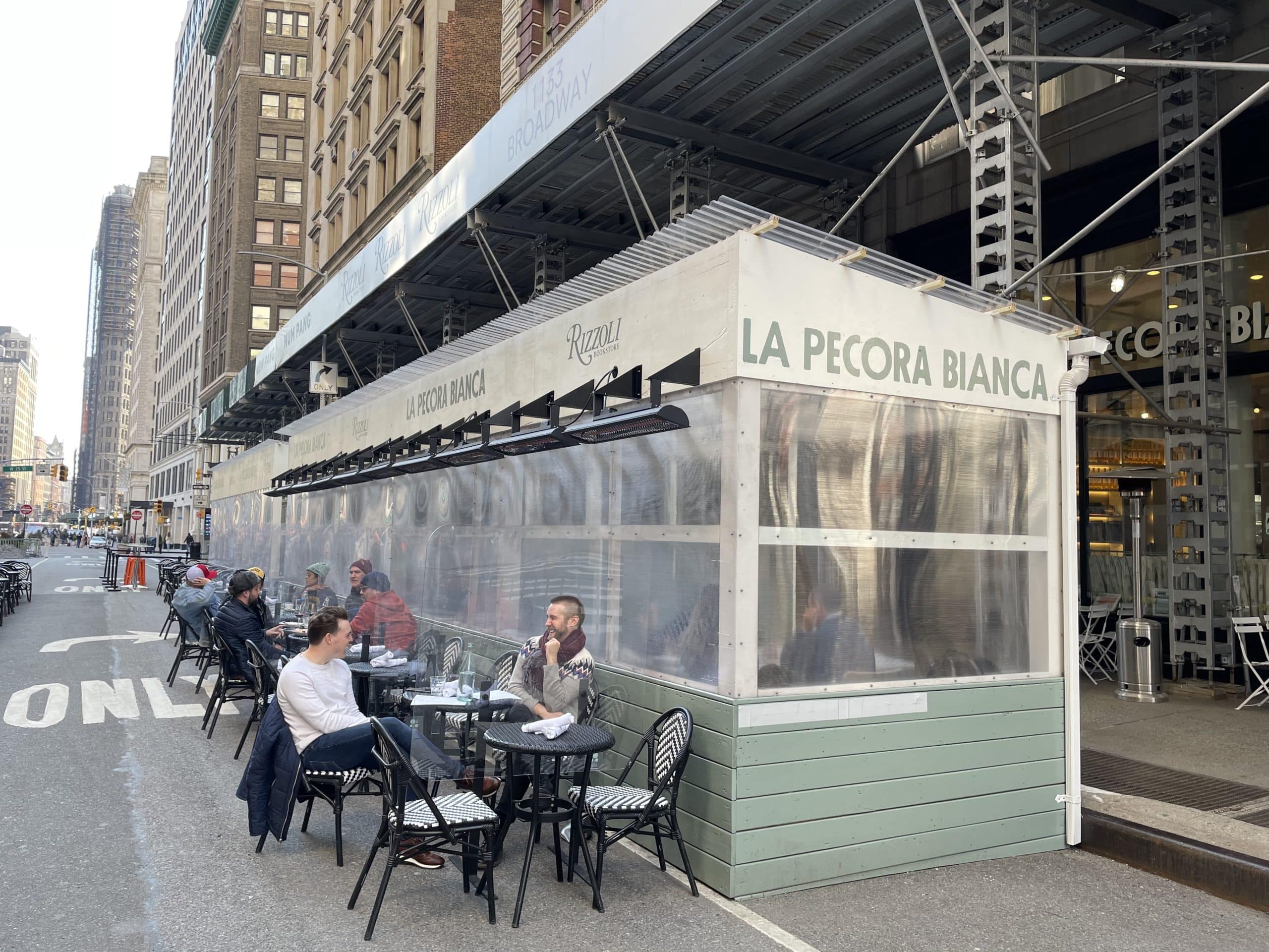 Las mesas del restaurante se extienden por la calle en Nueva York con calefactores eléctricos